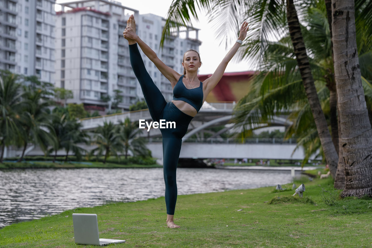 full length of young woman doing yoga at park