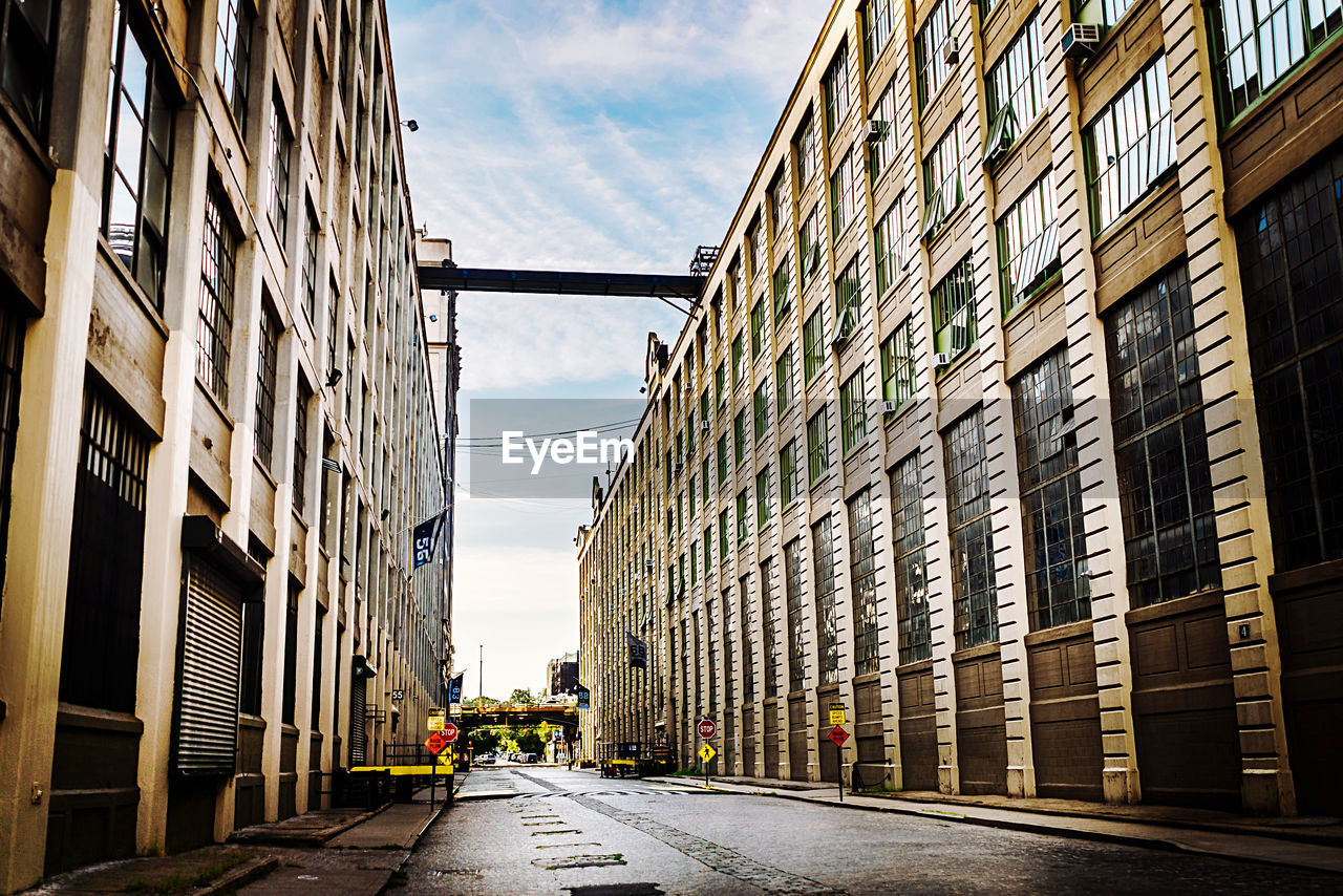 EMPTY ROAD AMIDST BUILDINGS AGAINST SKY