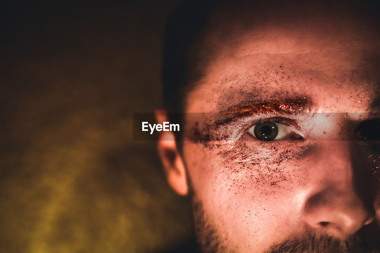 Close-up portrait of man with glitter eye make-up