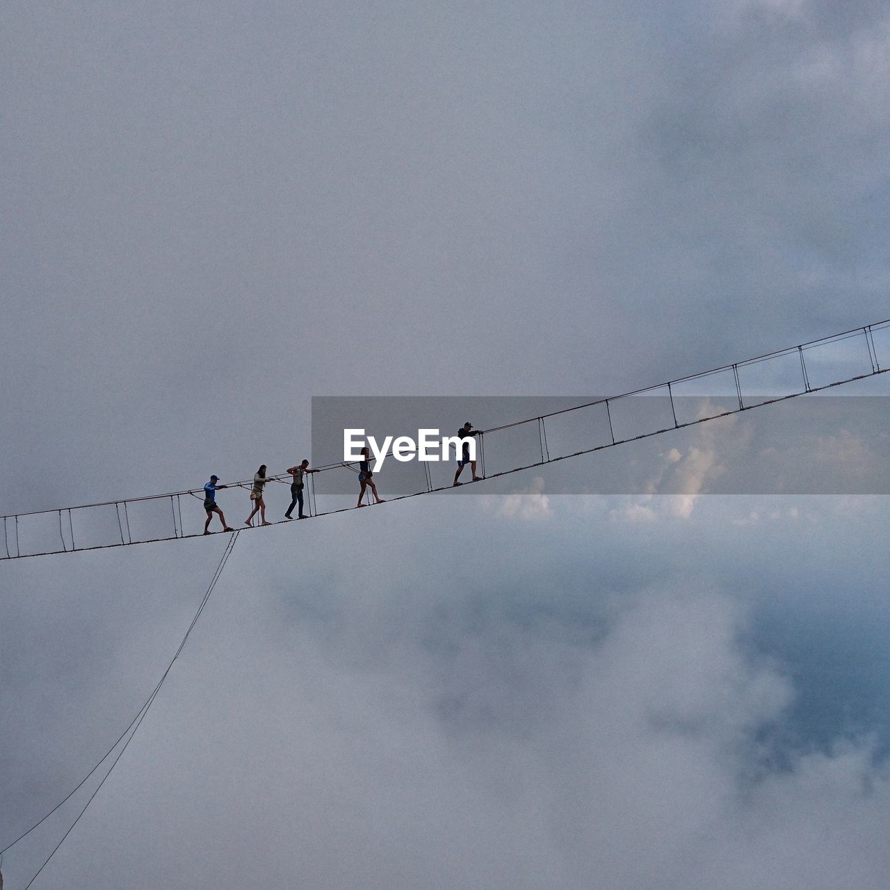 Low angle view of people on fragile bridge