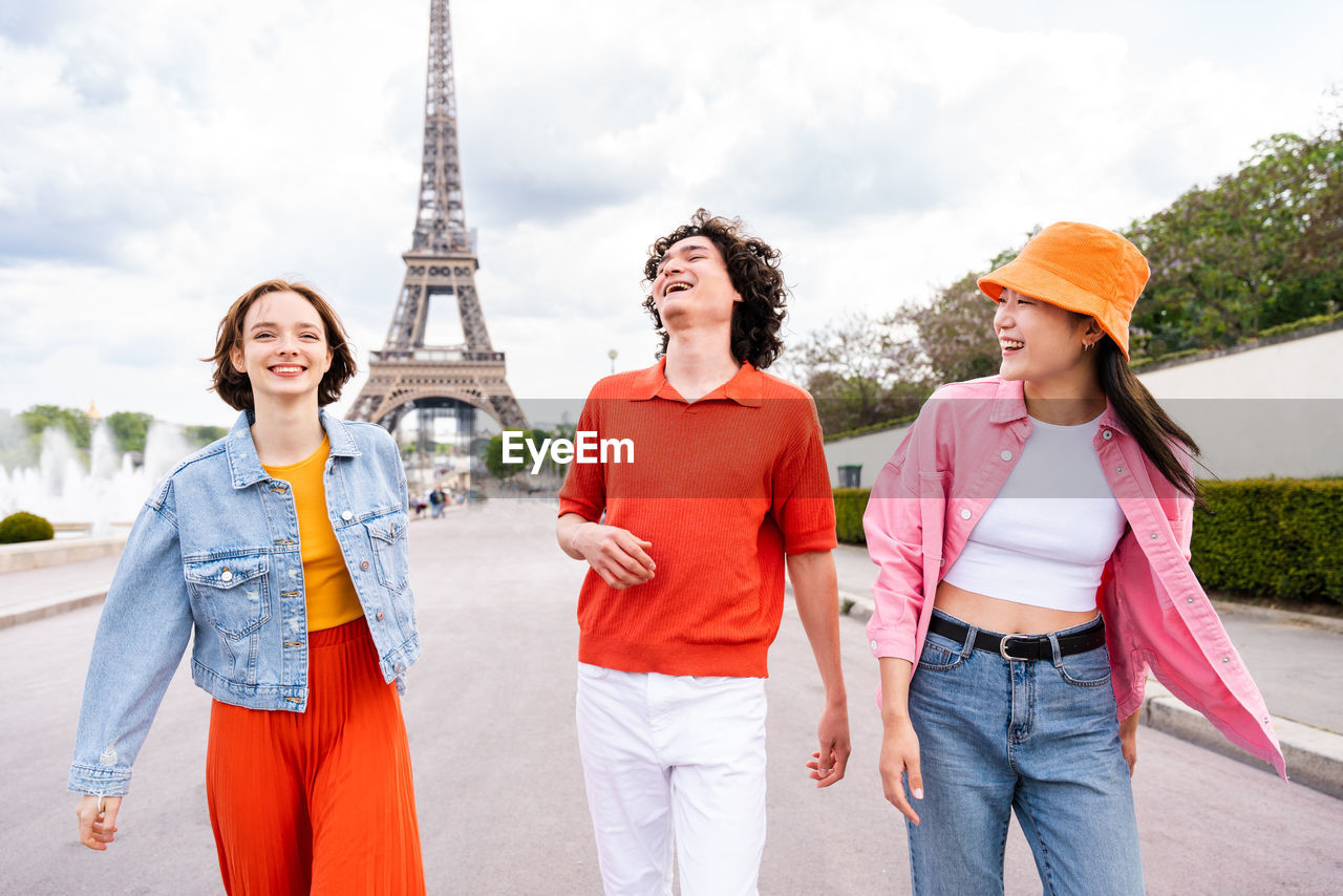 portrait of smiling friends standing against sky