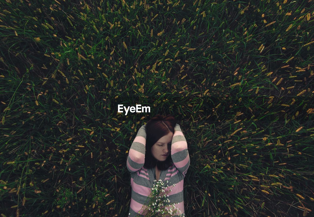 Directly above shot of young woman sleeping on grassy field