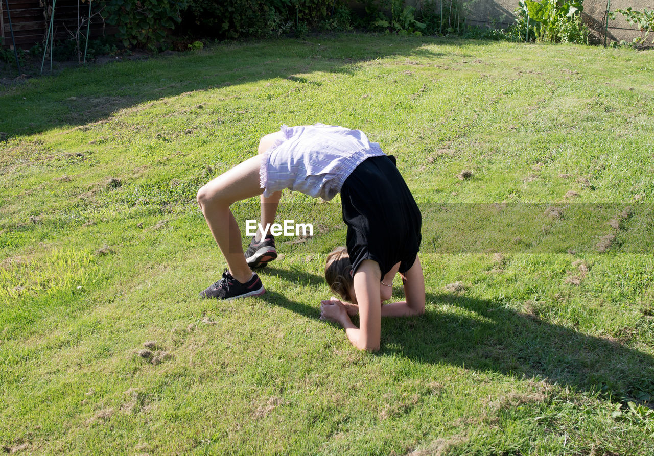 Teenage girl doing acrobatic exercises on a green lawn, sport, generation z,