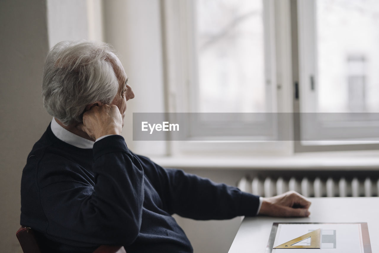 Senior man at home thinking with architectural plan on table