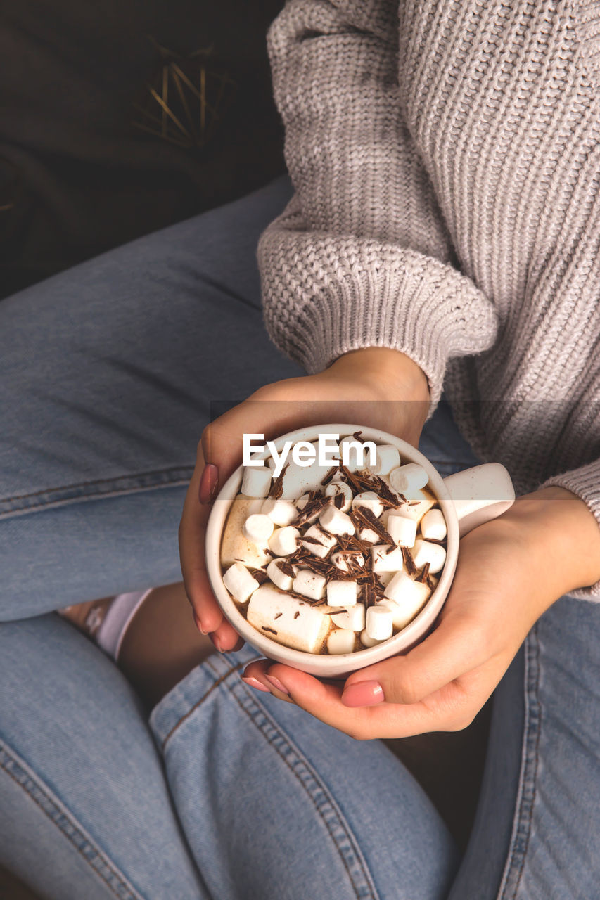 Midsection of woman holding coffee cup at home