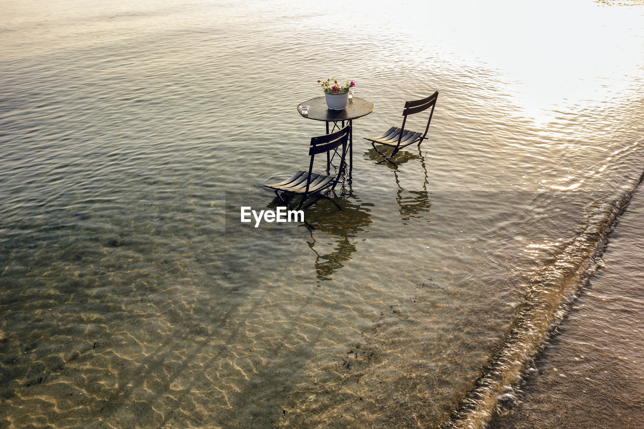 High angle view of chairs and table on sea