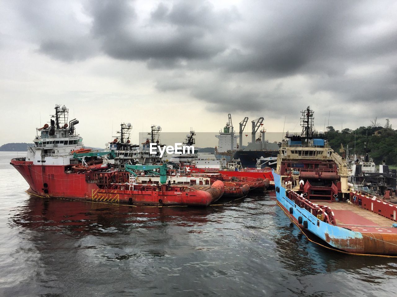 Boats sailing in sea against cloudy sky