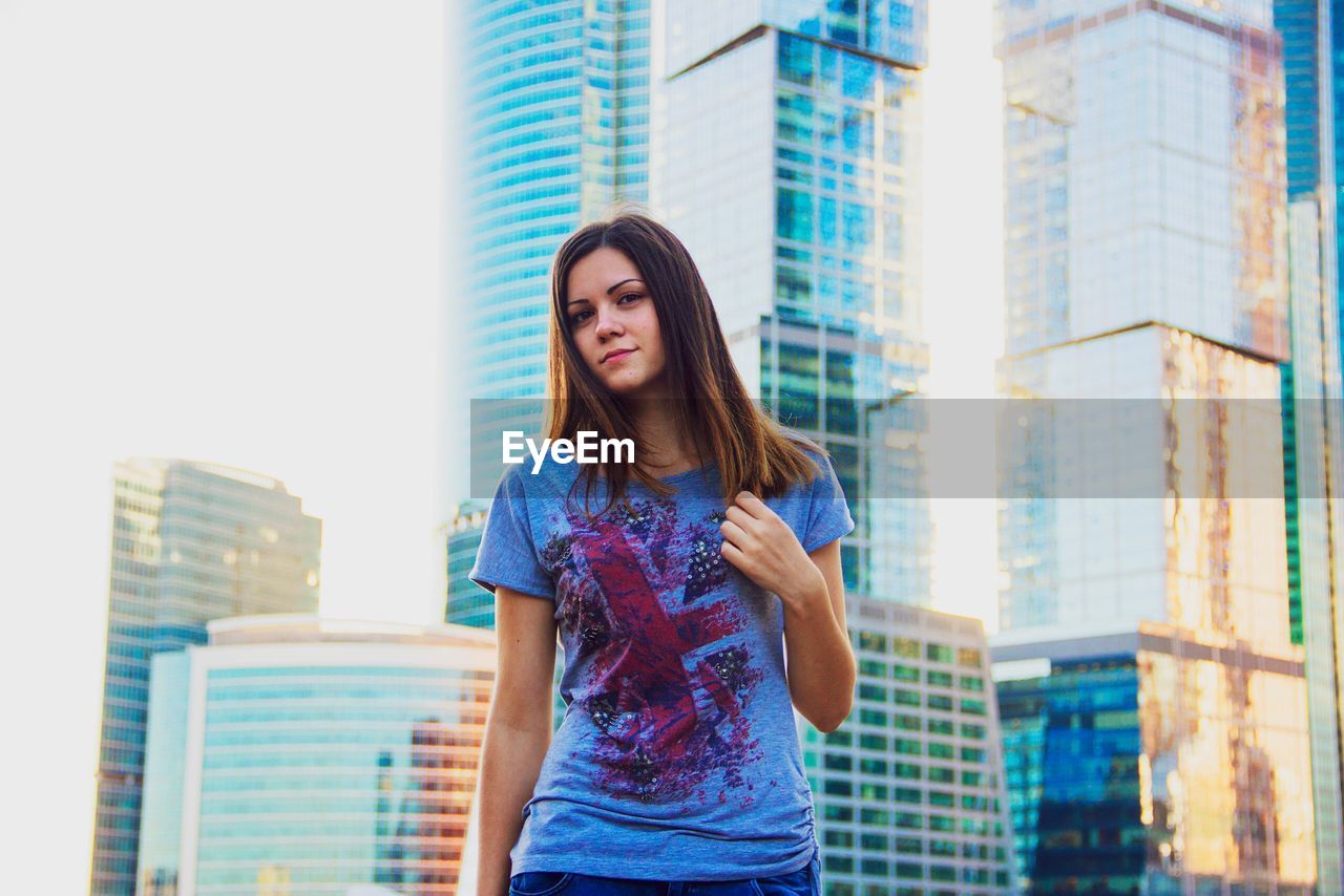 Young woman standing against modern office buildings