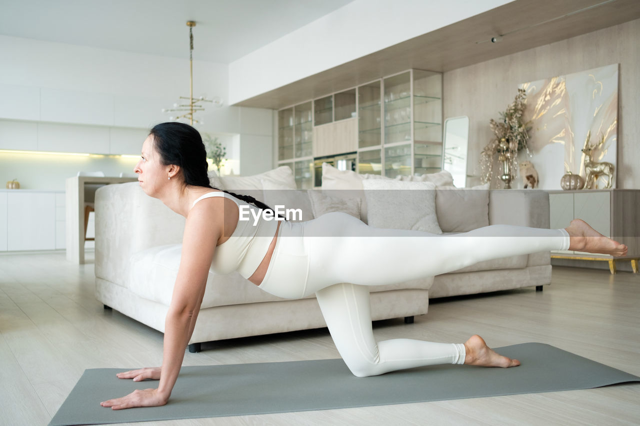 side view of woman exercising on floor at home