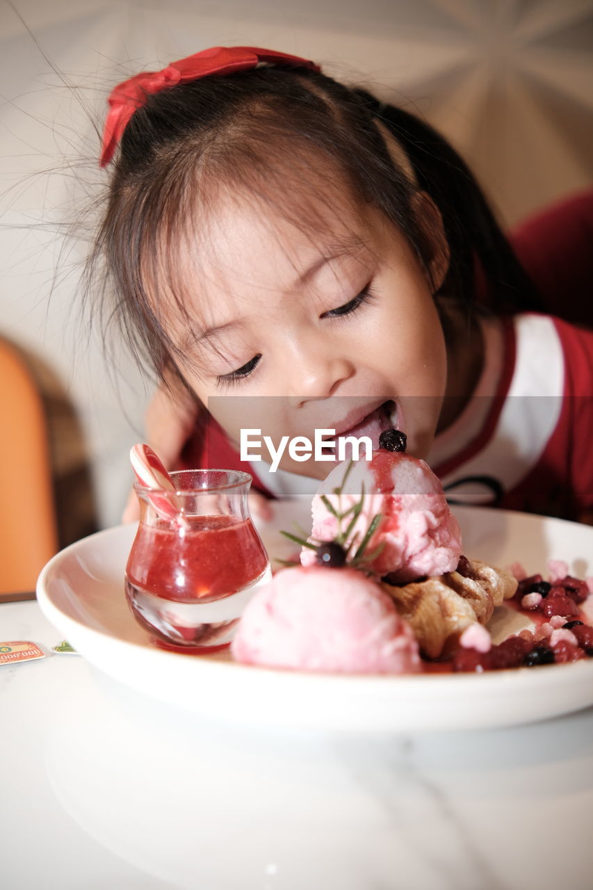 Portrait of kid with strawberry ice cream on table