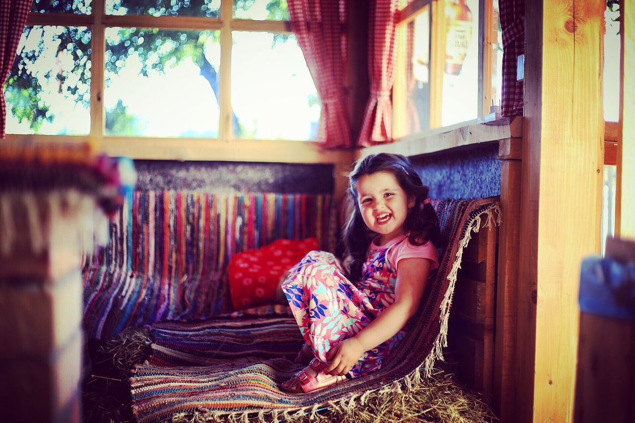 Portrait of smiling girl sitting on sofa at home