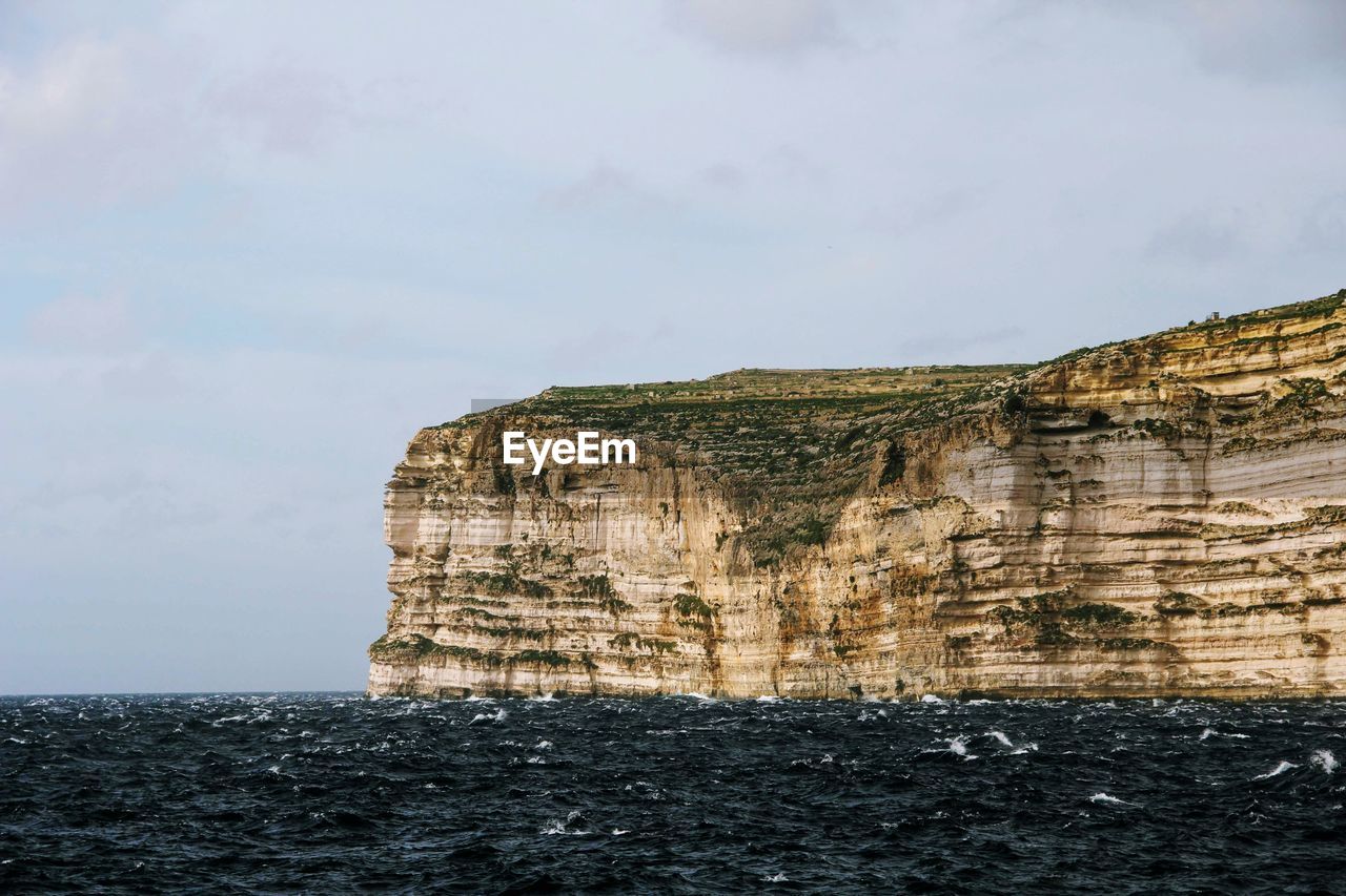 Rock formations by sea against sky