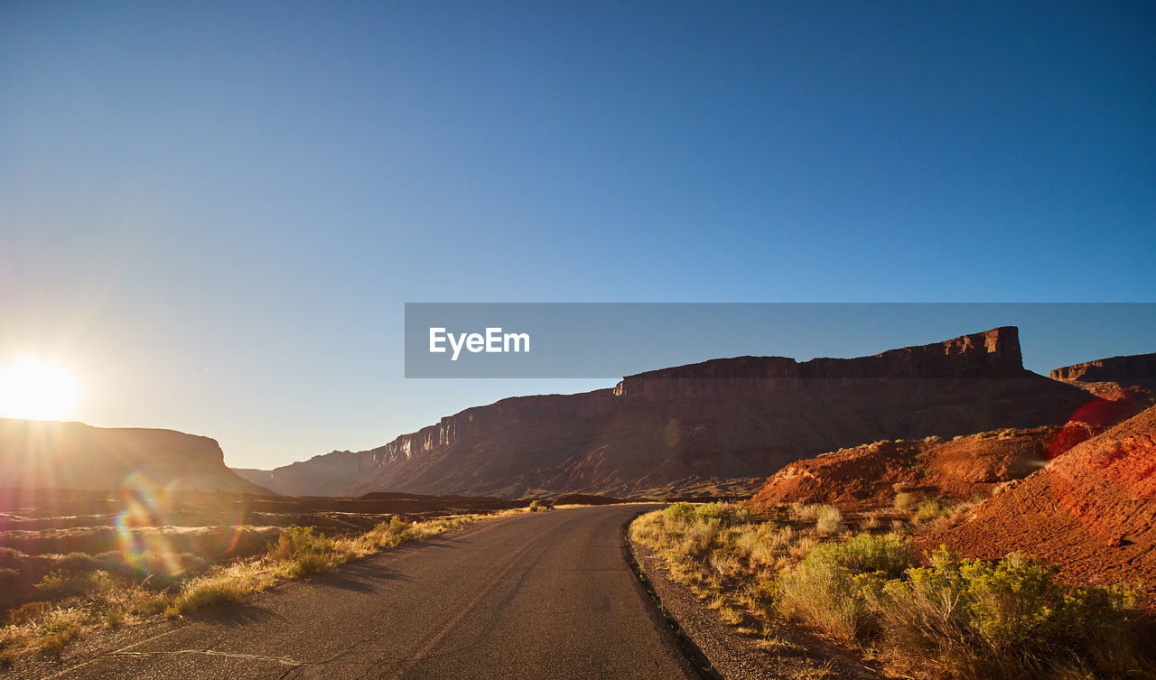Road by mountains against clear sky