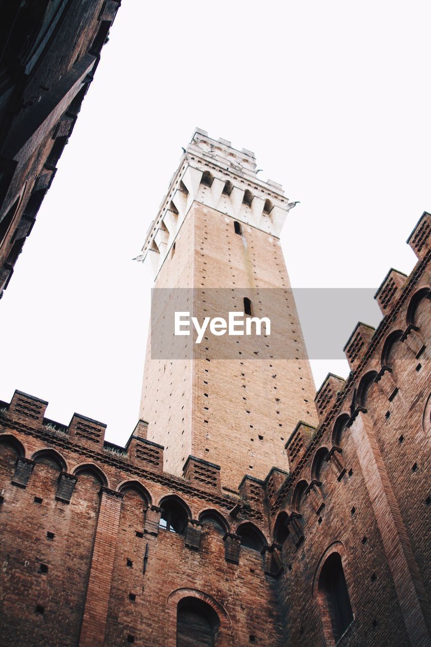 Low angle view of torre del mangia against clear sky in city