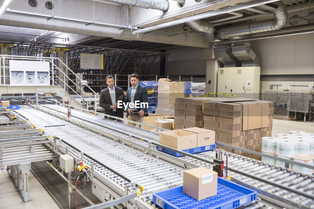 Two businessmen at conveyor belt in factory