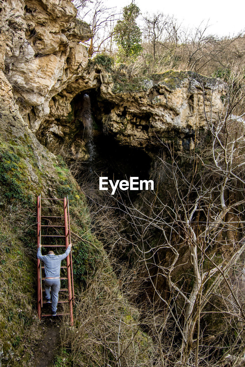 Rear view of man climbing on ladder