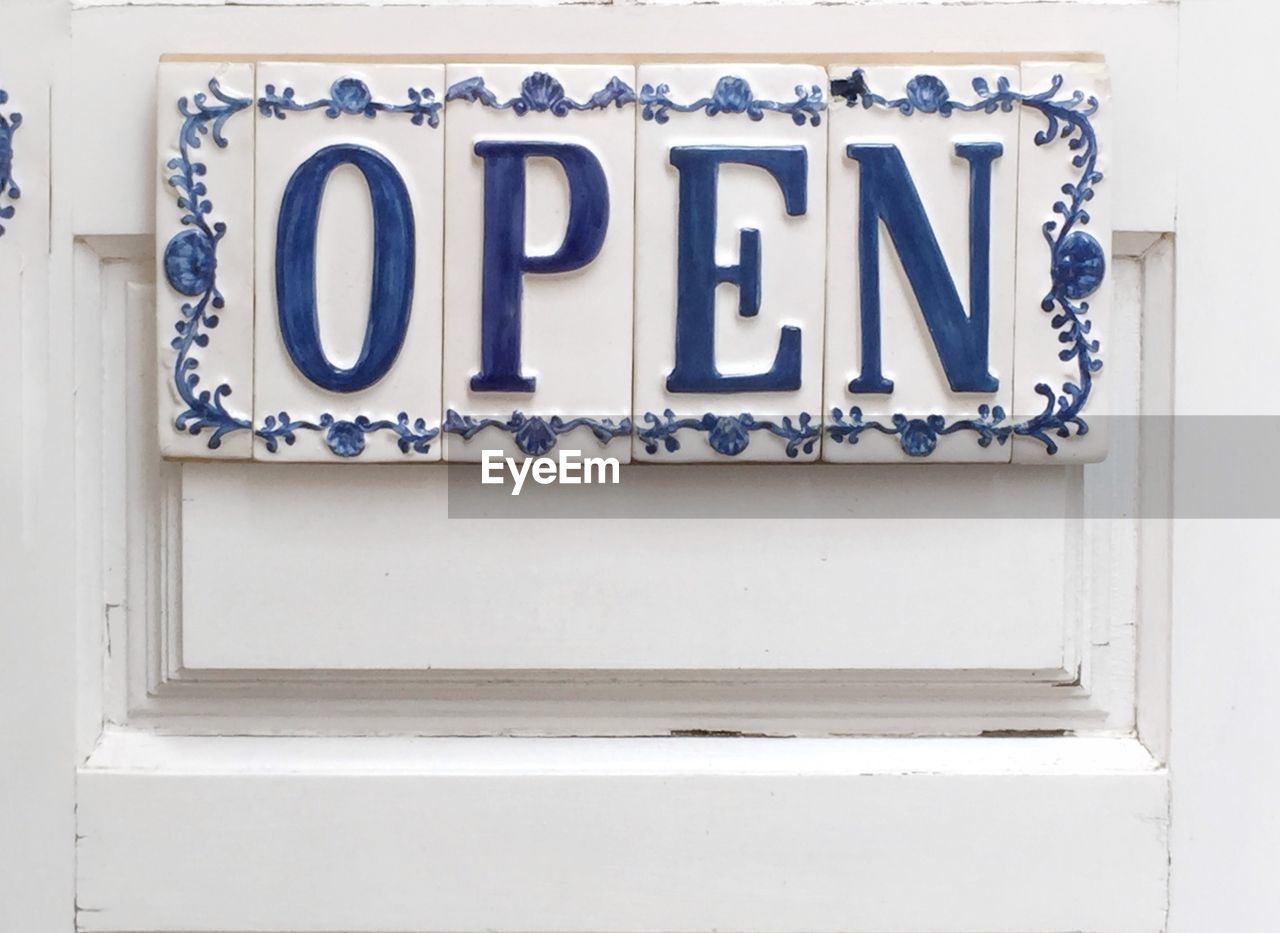 Close-up of open sign on white door