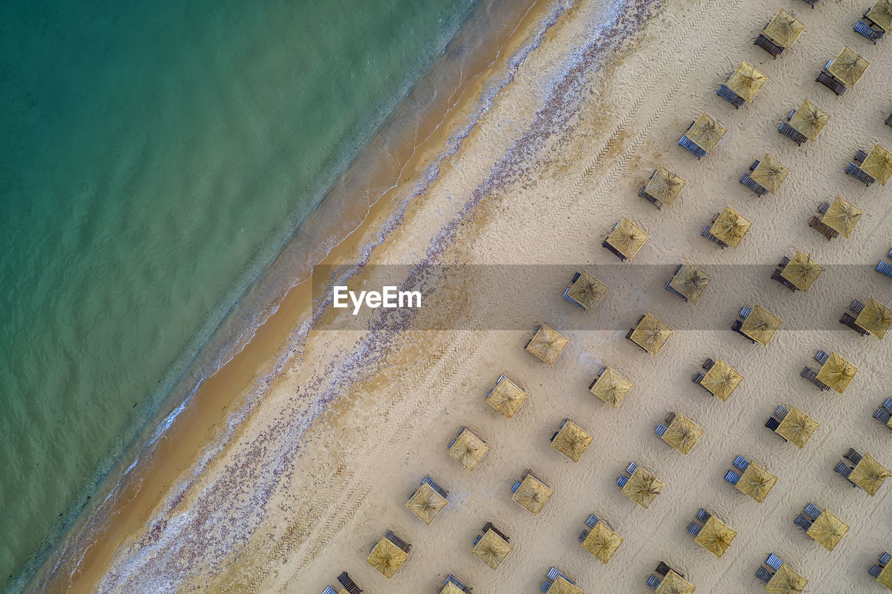 Aerial view of an amazing beach with wooden umbrellas, and calm sea.