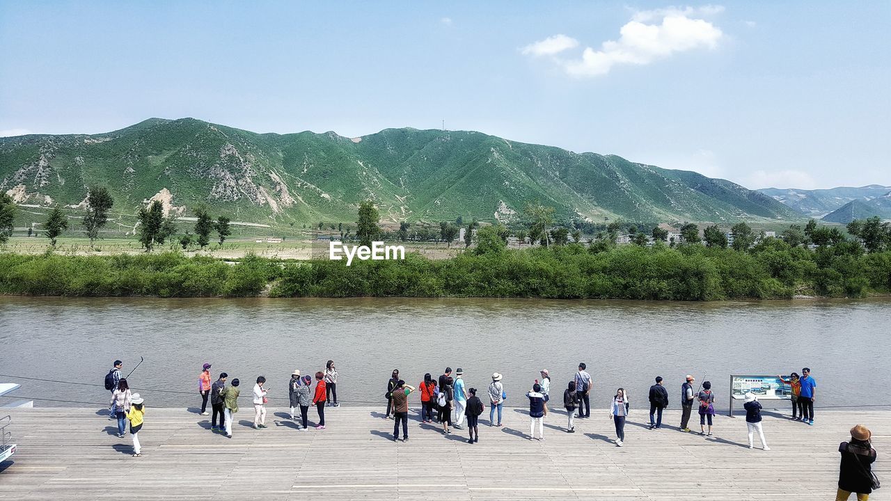 High angle view of people on promenade by river against sky