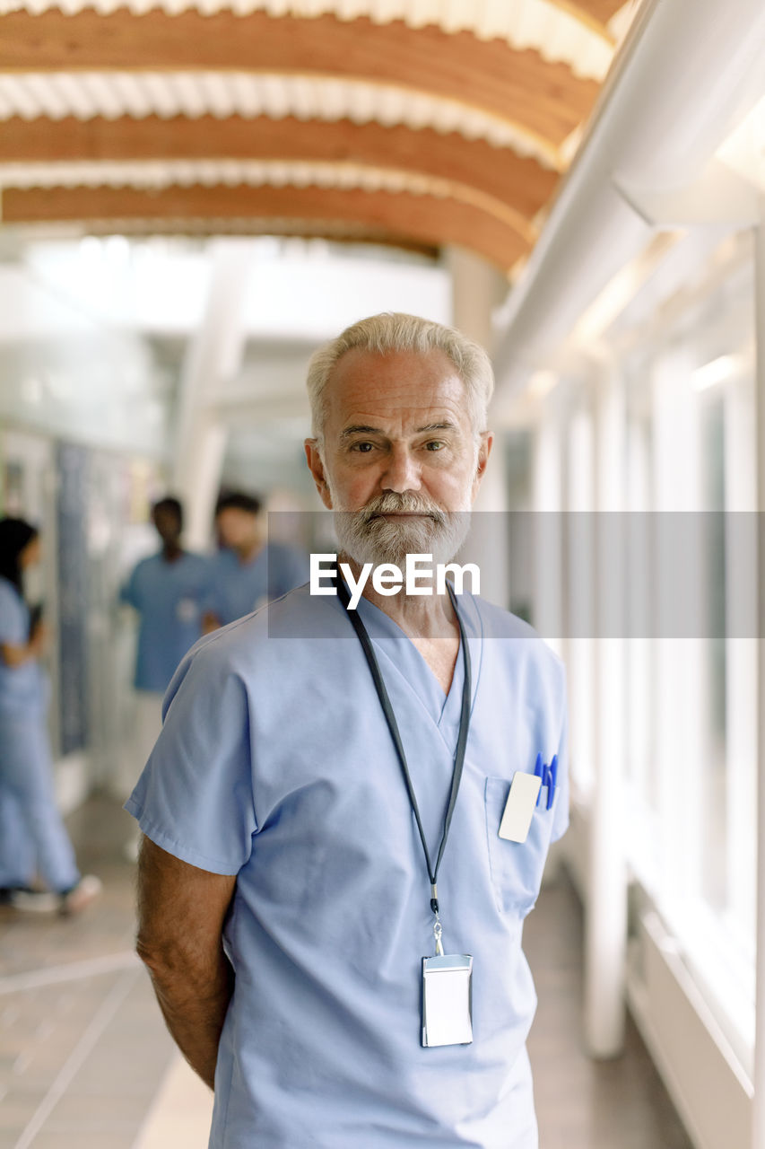 Portrait of wrinkled male nurse standing in hospital corridor