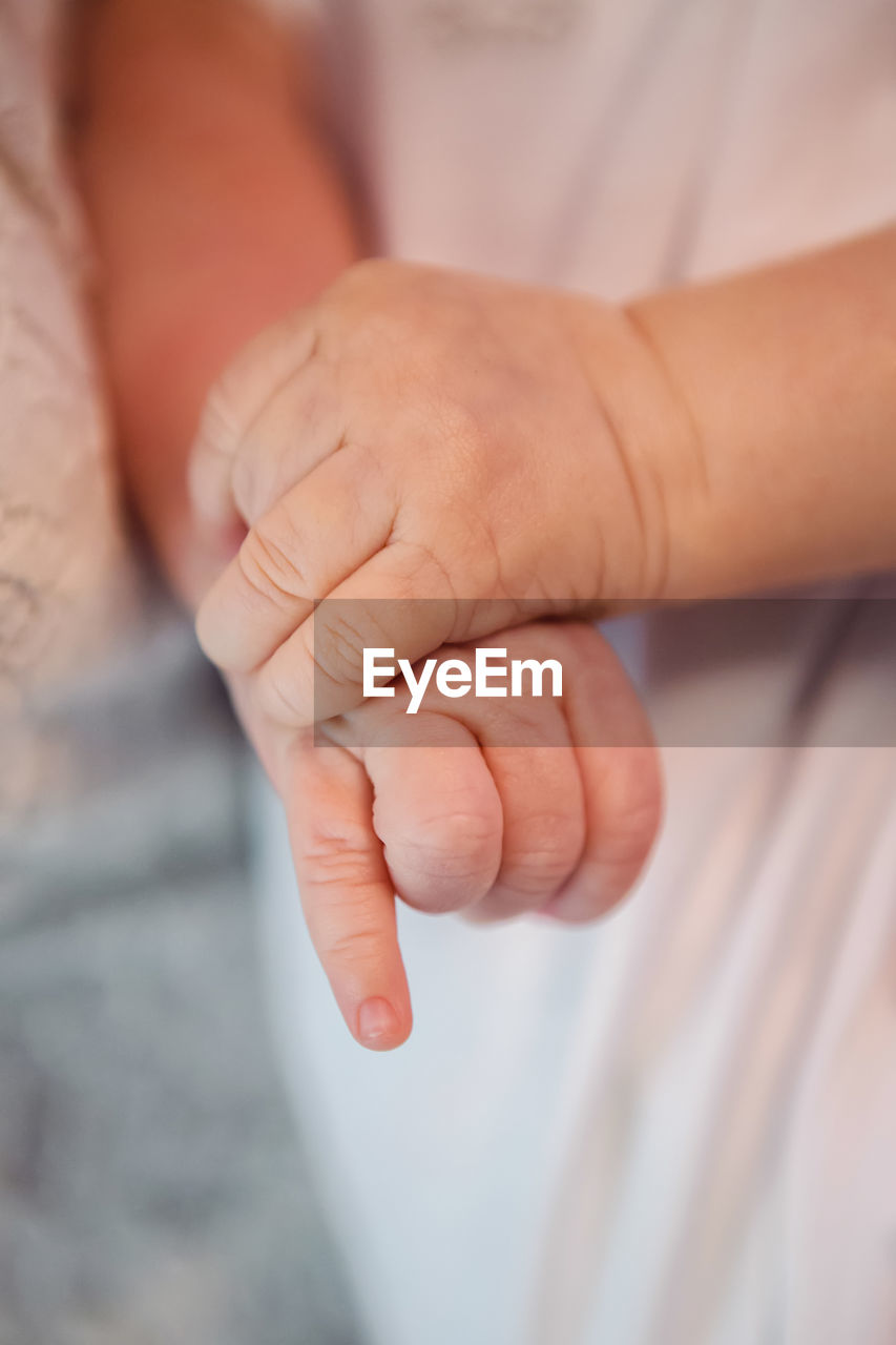 Hands of a newborn baby dressed in white