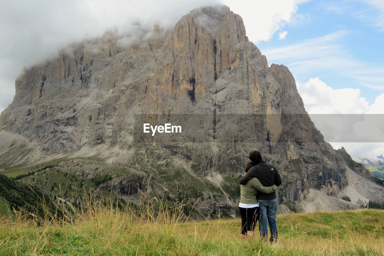 Rear view of couple embracing against dolomites mountain