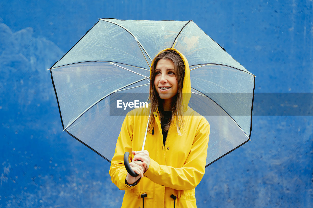 Woman holding umbrella against blue background