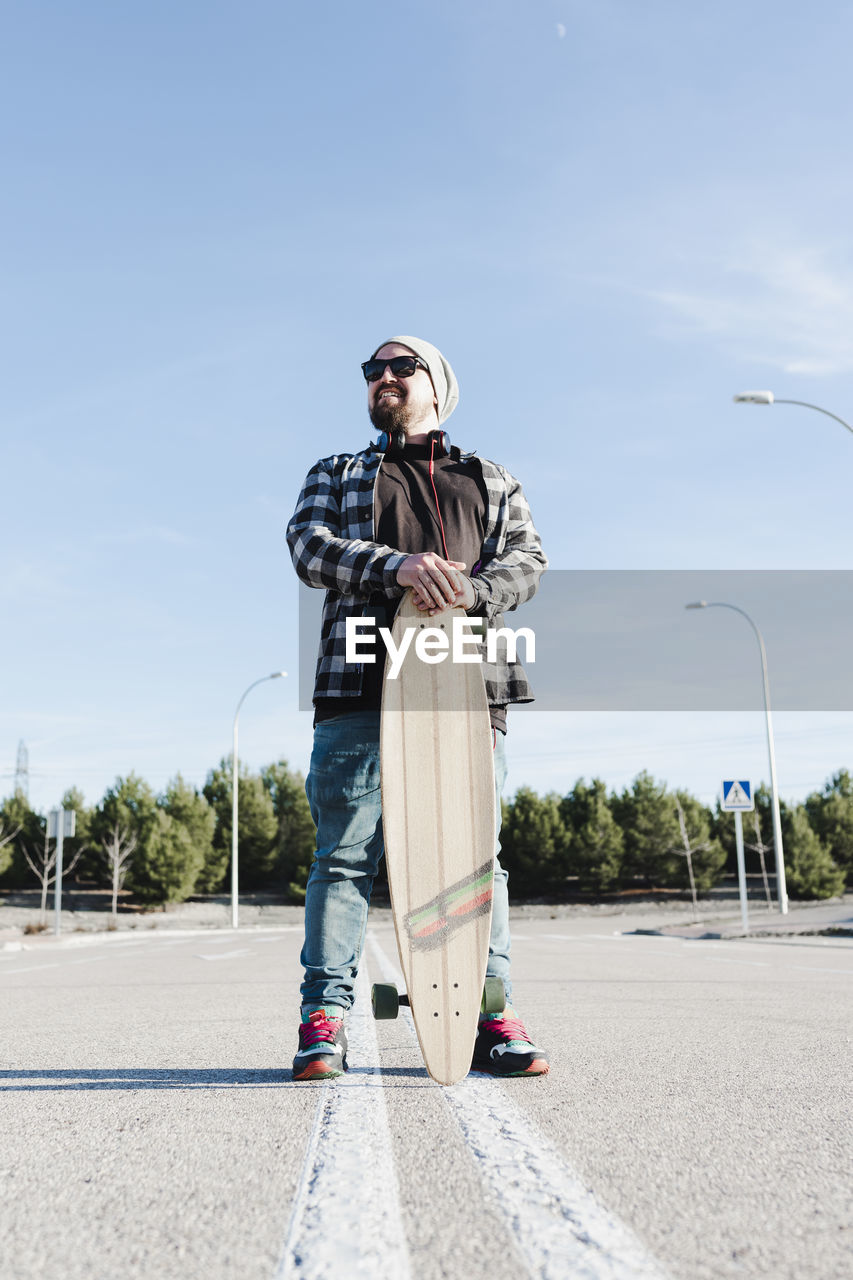 Portrait of a modern man holding the longboard.