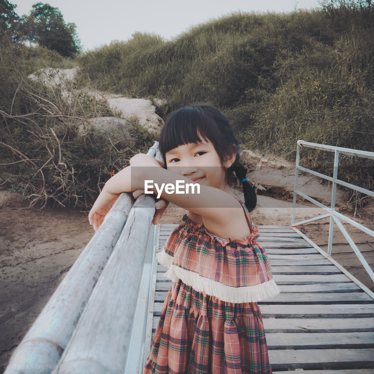 Portrait of smiling girl standing on footbridge