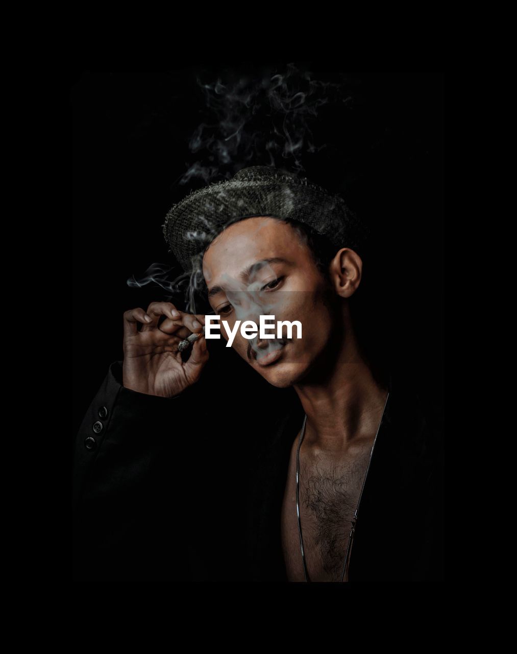 Man smoking cigarette against black background