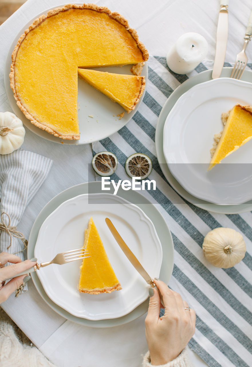 Cropped hands of woman having cake in plate on table