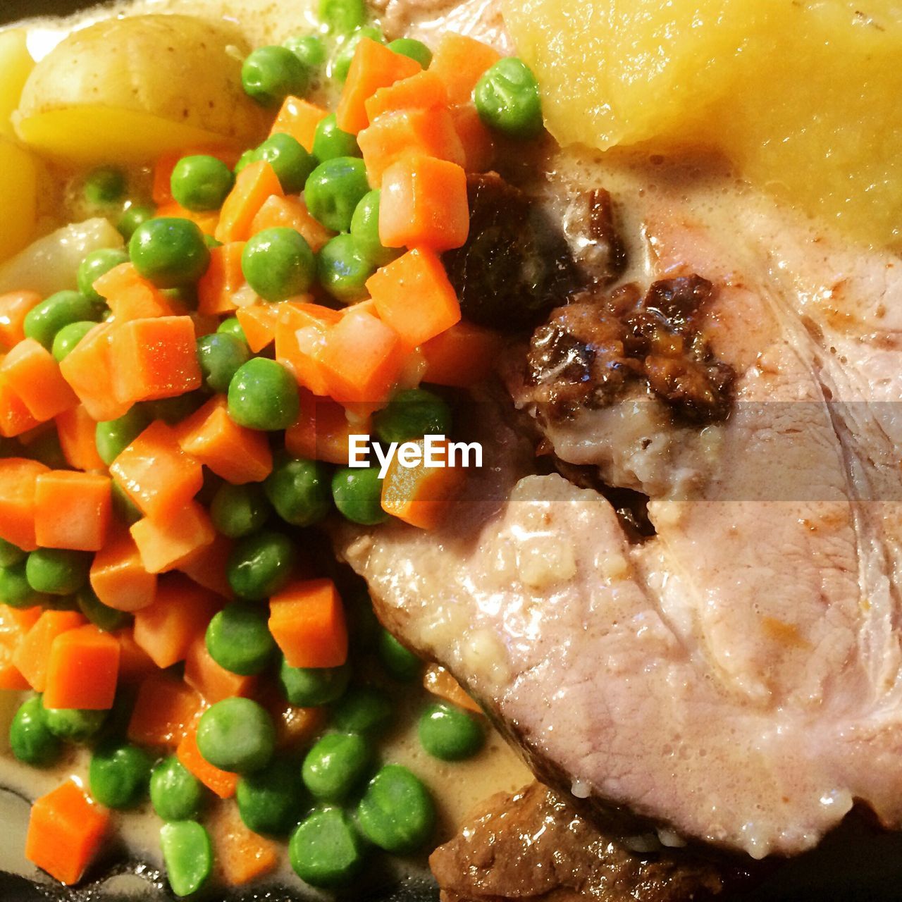 Close-up of pork with green peas served