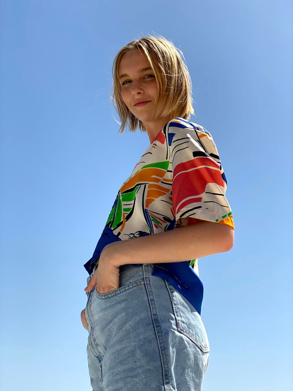 Low angle portrait of woman standing against clear blue sky