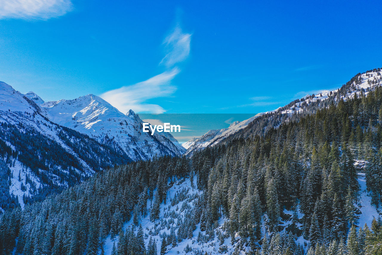 Scenic view of snowcapped mountains against blue sky