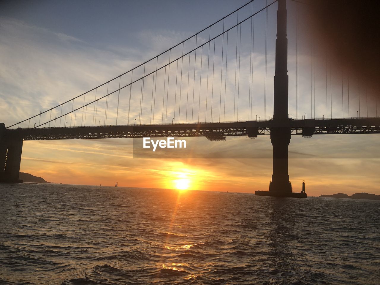 View of suspension bridge over sea during sunset