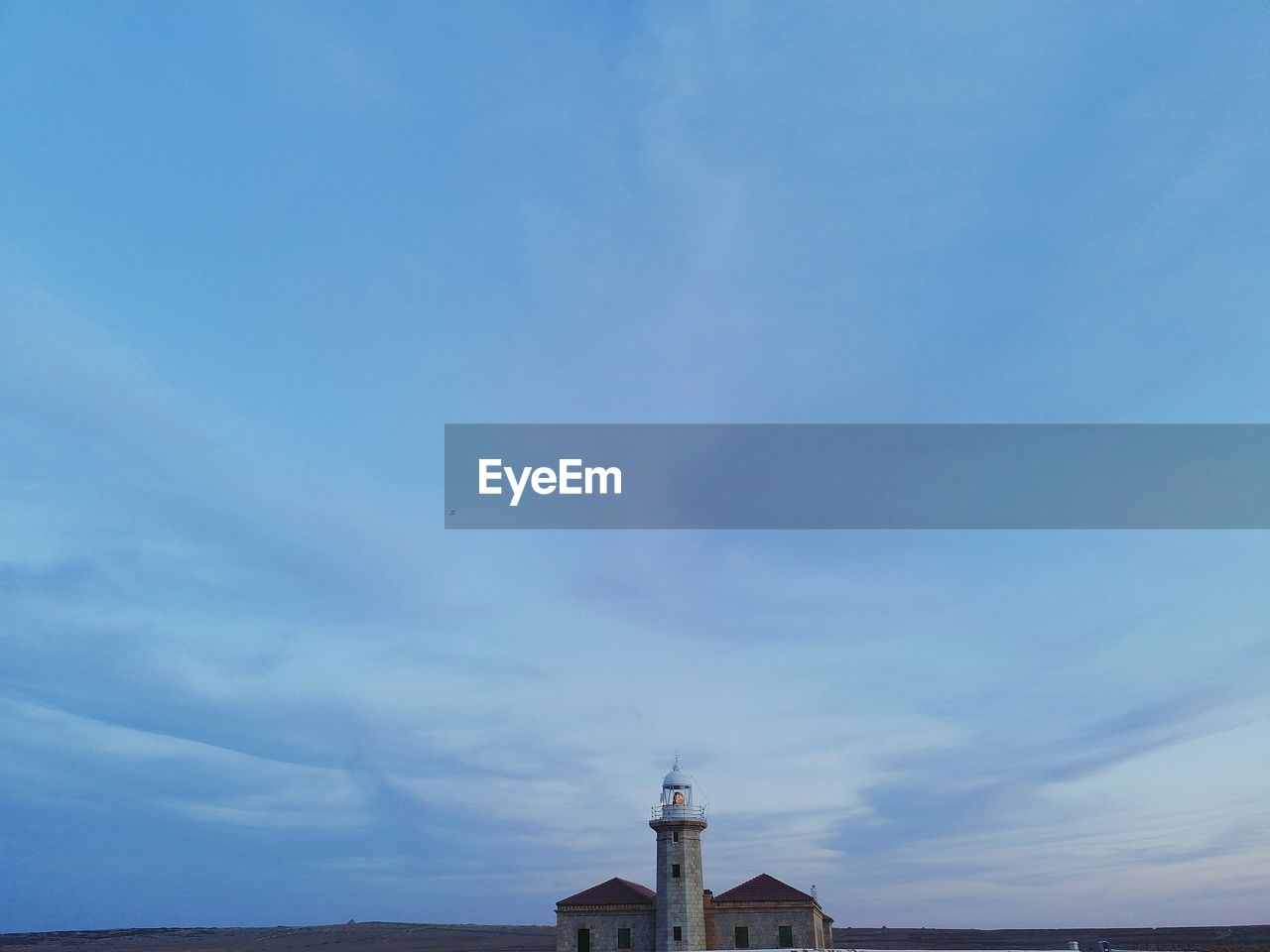 LOW ANGLE VIEW OF LIGHTHOUSE AGAINST BUILDING