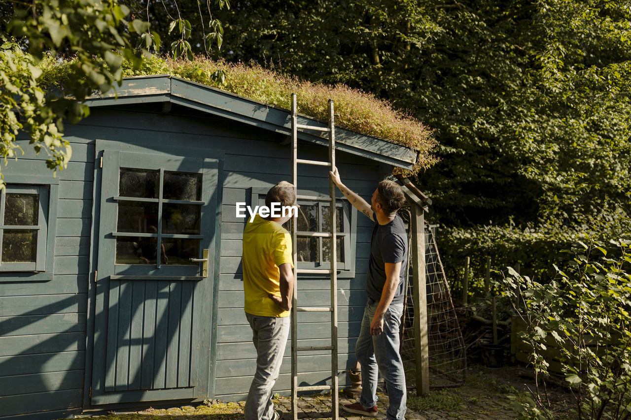 Father and son holding ladder in front of house