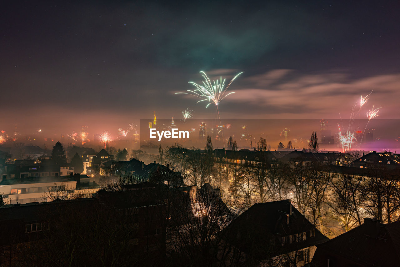 FIREWORK DISPLAY OVER CITY BUILDINGS AGAINST SKY