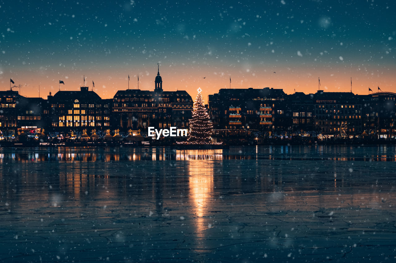 View of hamburg's snowy inner city with its illuminated christmas tree on the alster lake