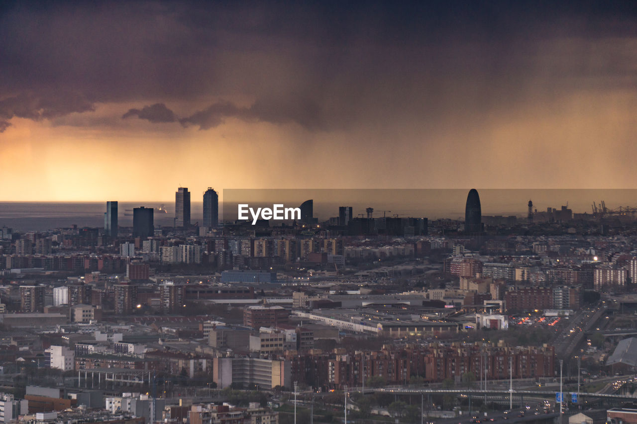 HIGH ANGLE VIEW OF BUILDINGS IN CITY AGAINST SKY DURING SUNSET