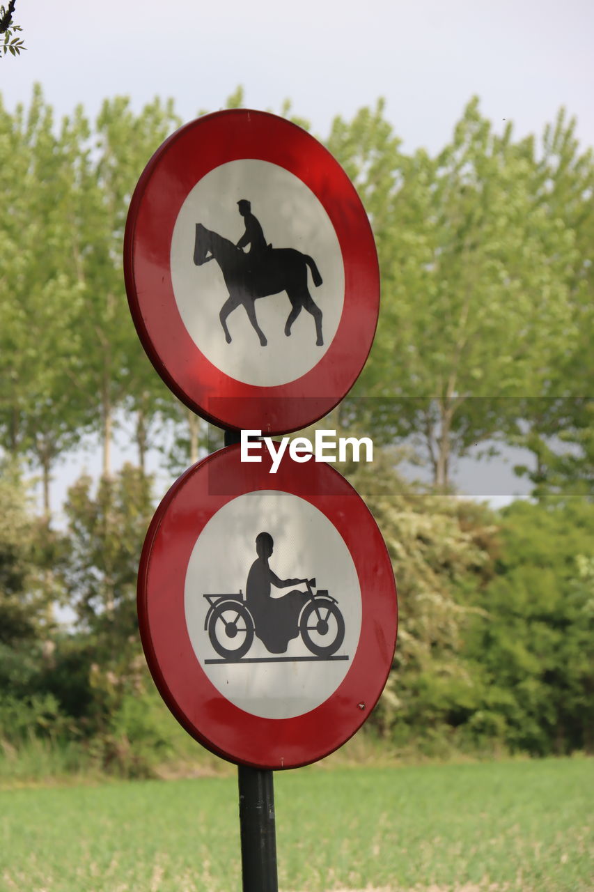 communication, sign, tree, traffic sign, plant, no people, road sign, circle, nature, day, geometric shape, shape, road, signage, representation, guidance, outdoors, warning sign, close-up, symbol, red, focus on foreground