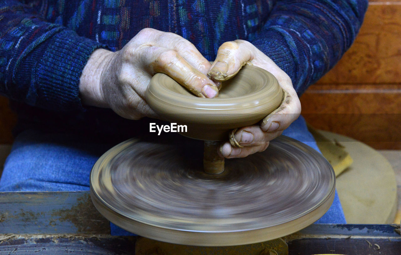 Craftsperson shaping pot on pottery wheel