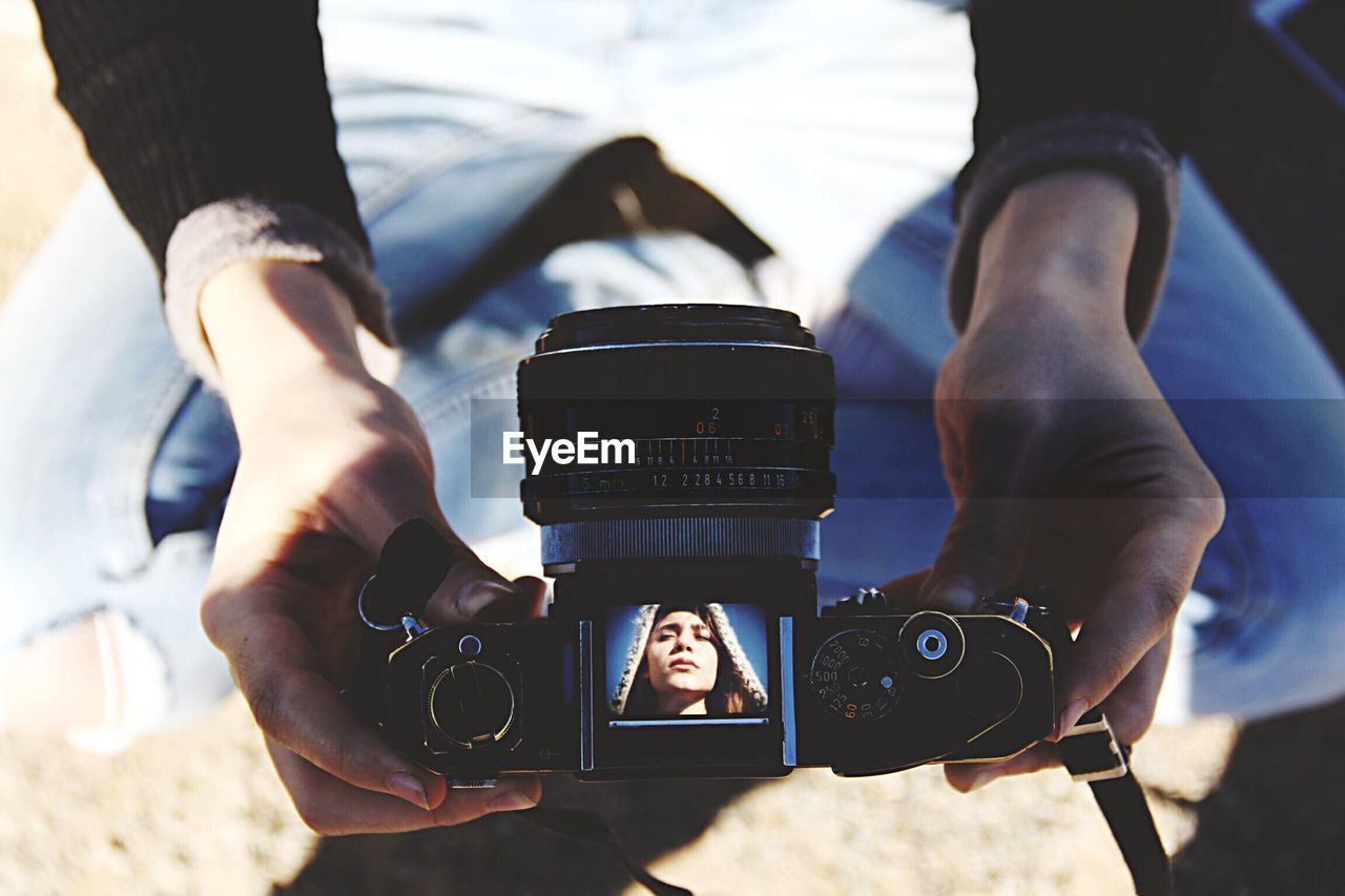 Low section of woman holding camera at beach