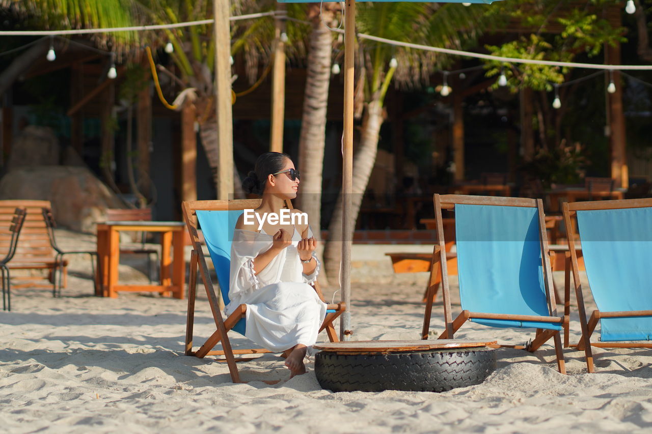 Young woman sitting on chair at beach