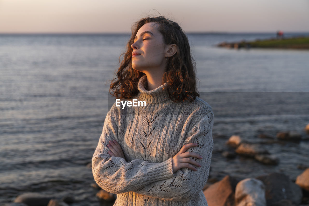 Smiling young woman with eyes closed enjoying sunset