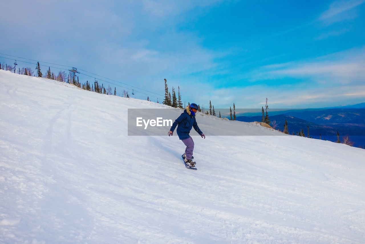 Full length of man snowboarding on snow covered mountain