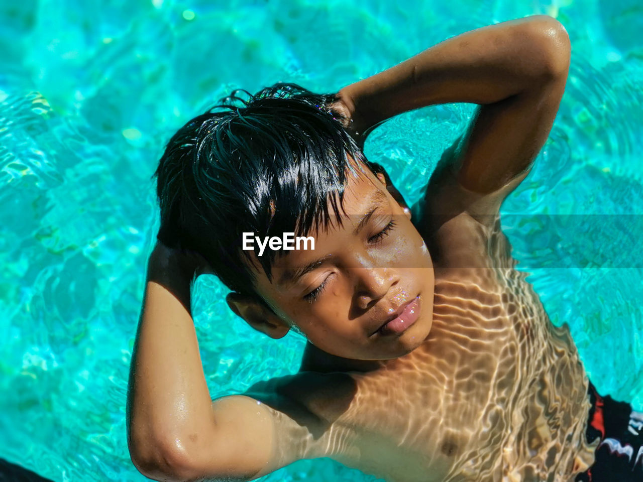 High angle portrait of smiling boy swimming in pool