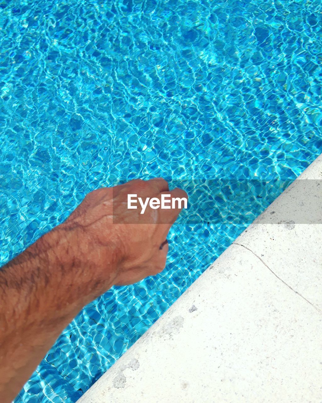 HIGH ANGLE VIEW OF MAN SWIMMING IN POOL