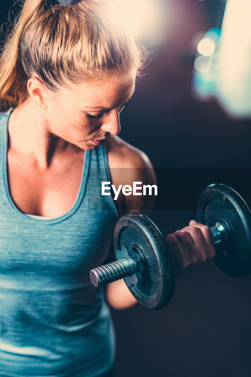 Close-up of mid adult woman lifting dumbbell