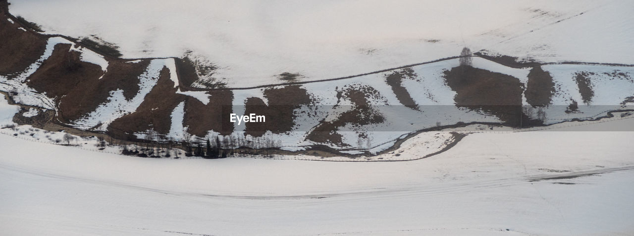 HIGH ANGLE VIEW OF SNOW COVERED LAND AND TREES AGAINST SKY